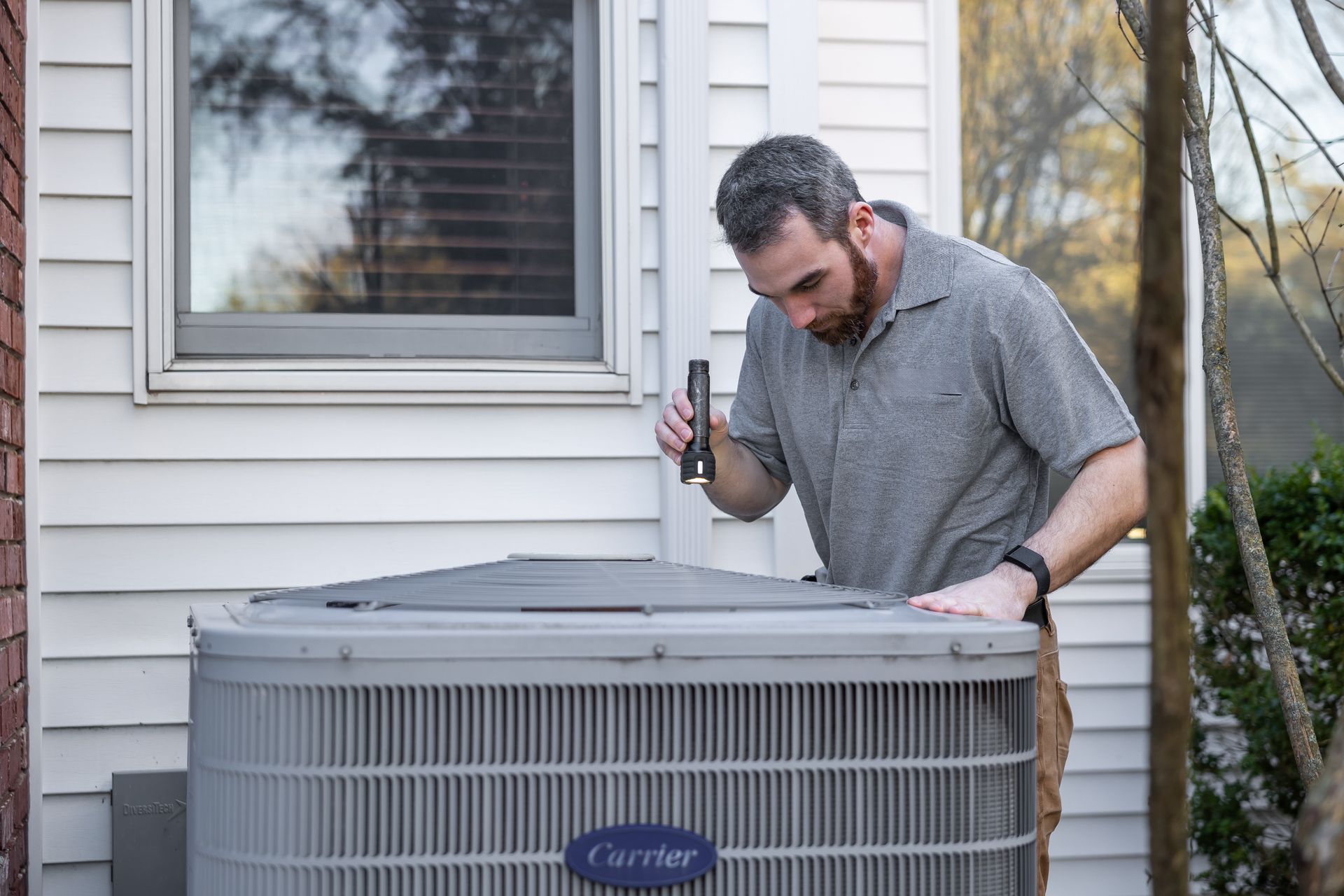 Technician inspecting a home air conditioning condenser
